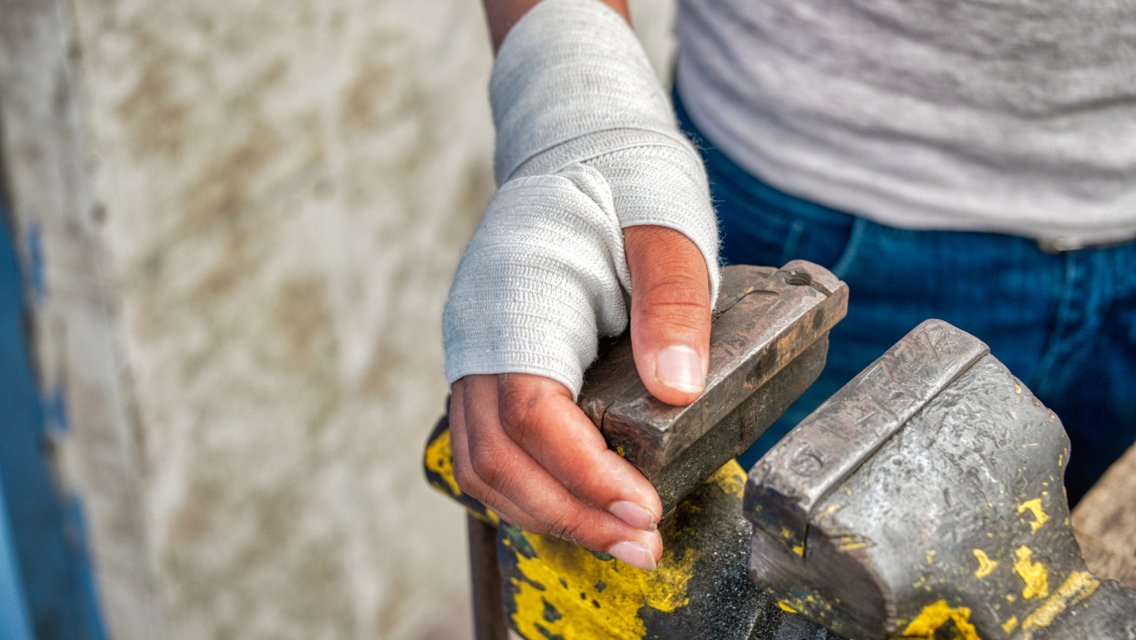 A bandaged hand resting on a vice grip