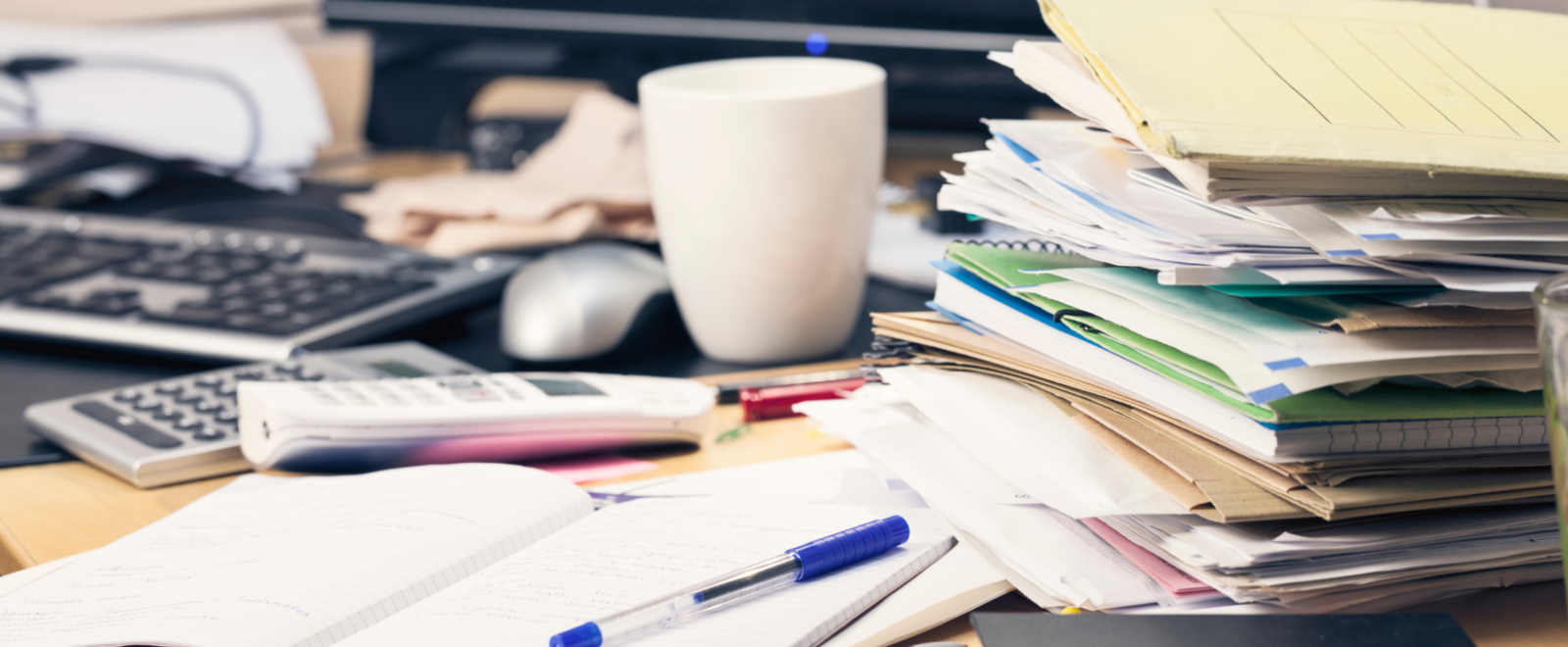 A messy desk covered in file folders.