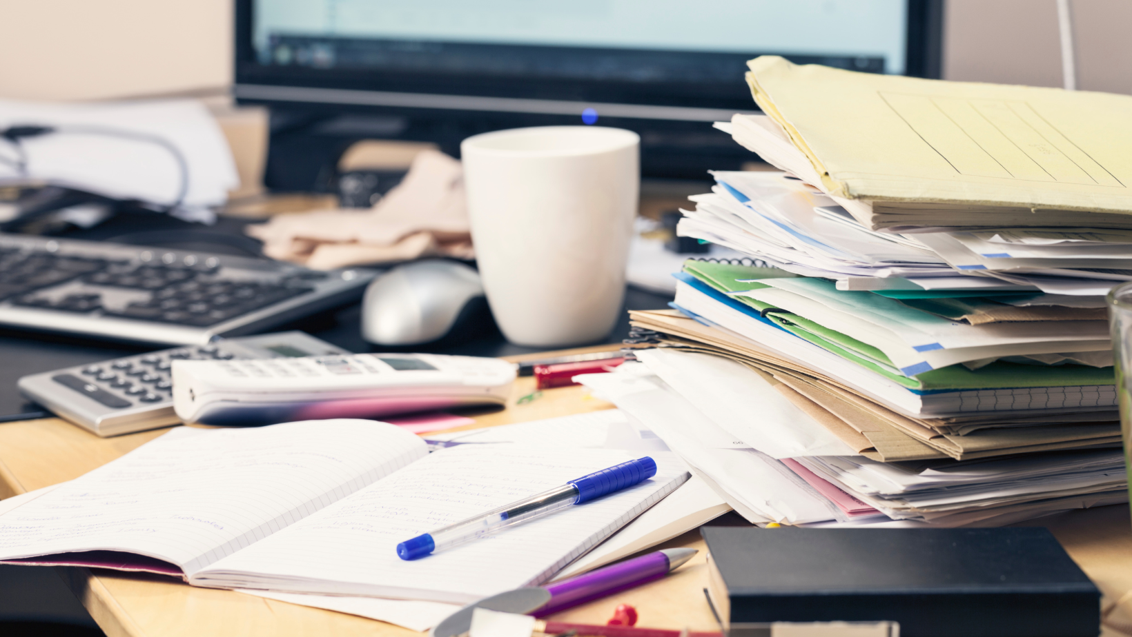 A messy desk covered in file folders.