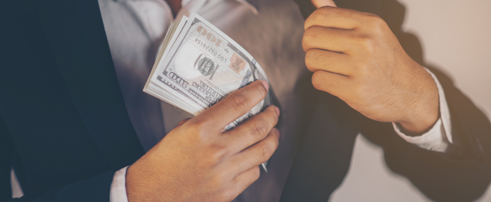 A man putting money in his jacket pocket.