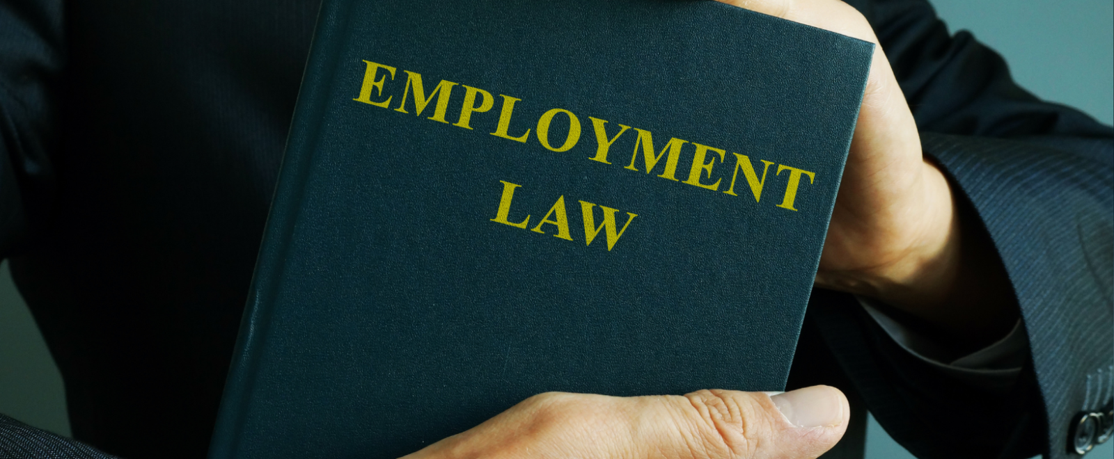 Man holding book titled, "Employment Law"