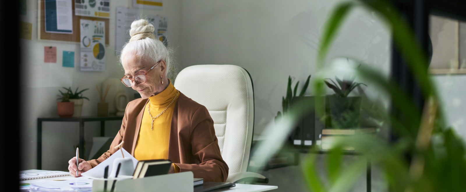 White-haired woman working at a desk.