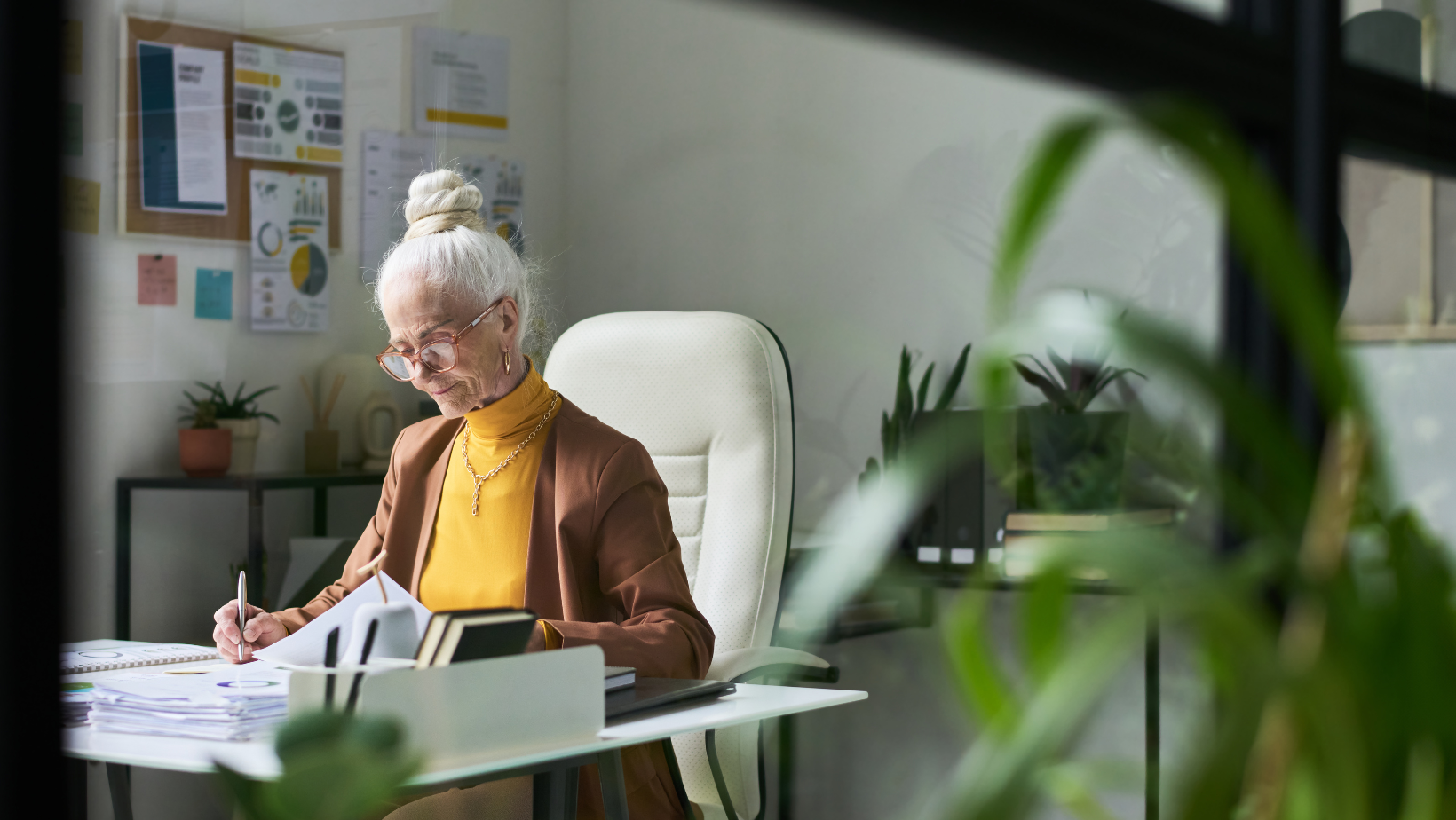 White-haired woman working at a desk.